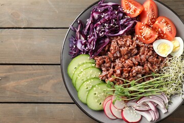 Tasty salad with brown rice on wooden table, top view