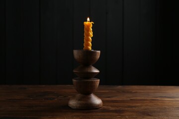 Burning candle in candlestick on wooden table