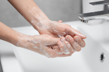 Fototapeta premium Woman washing hands at sink in bathroom, closeup