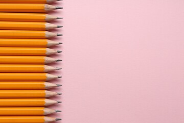 Sharp graphite pencils on pink background, flat lay. Space for text