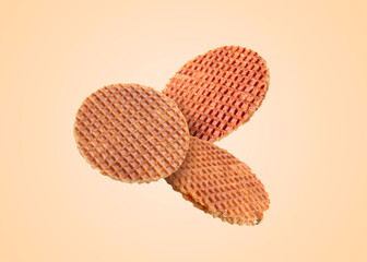 Yummy Dutch waffles (stroopwafels) flying on beige background