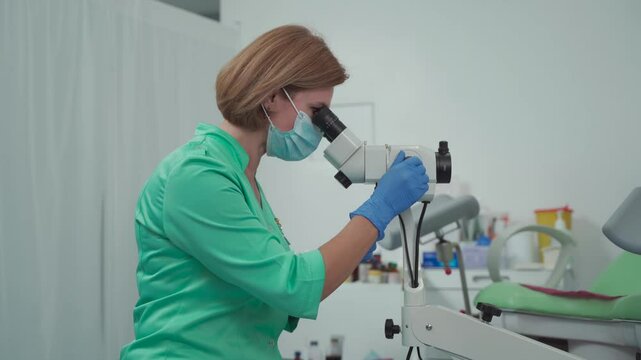 Gynecologist uses colposcope. Optical device with magnification designed for detailed examination of cervix, vagina, and vulva, aiding in diagnosing pathologies and detecting precancerous changes. 