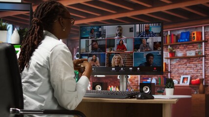 Remote employee in home office saluting colleagues during online videocall, looking at PC screen. Businesswoman in apartment greeting team members during videoconference meeting, camera A