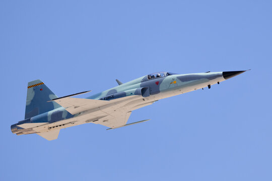 bottom view  of a F-5E Tiger II in the aggressor color scheme, approaching in beautiful light