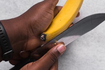 Hands peeling ripe plantains, yellow plantains for frying being peeled, process for making fried plantain © this_baker