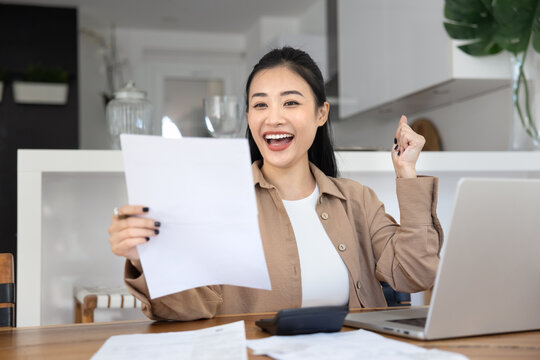 Excited Asian woman celebrate great financial news written in legal documents, notification or letter, reading about tax refund confirmation, loan approval, successful investment statement, promotion