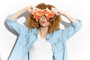 Young woman playfully holding pizza slices in front of her face, showcasing joy and personality...