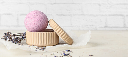 Lavender bath bomb on table near light brick wall