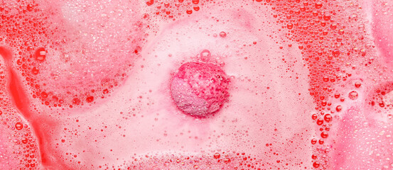 Bath bomb dissolving in pink water