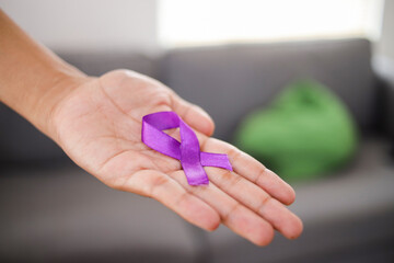 Closeup of Man Hand With Purple Ribbon as Symbol of World Cancer Day