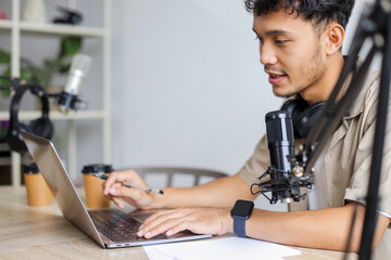 Young Blogger Man Recording Online Podcast Using Laptop and Professional Microphone.