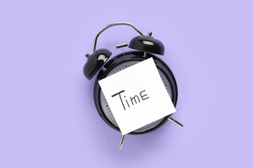 Paper with word TIME and alarm clock on lilac background. Top view
