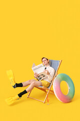 Office worker with inflatable ring and flippers sitting on deck chair and reading newspapers on...
