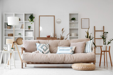Interior of light living room with beige couch, lamp and plants