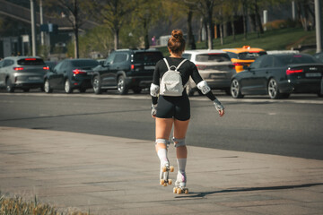 a woman on roller skates rides on the sidewalk