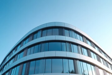 Modern curved glass office building with reflective windows under clear blue sky