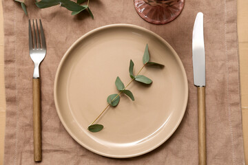Beautiful table setting with eucalyptus on beige wooden background
