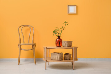 Vase with bamboo stems and wicker baskets on coffee table in living room, closeup