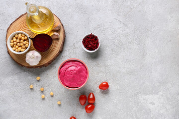 Bowl of tasty beet hummus with tomatoes, peas and garlic on grey background