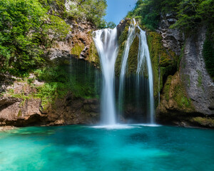 Obraz premium High-quality symmetrical image of a waterfall cascading down rocky cliffs into a turquoise pool