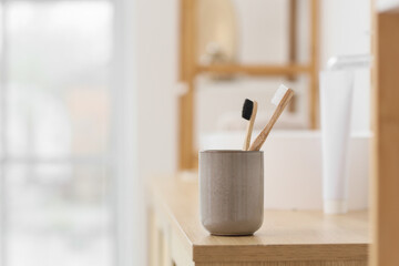 Holder with bamboo tooth brushes on table in bathroom