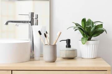Fototapeta premium Holder with bamboo tooth brushes and paste on stand near sink in bathroom