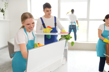 Young janitors cleaning desk in office