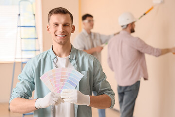 Young man with paint color palettes in room