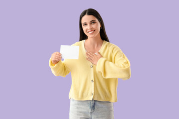 Thankful young woman holding empty paper sheet on lilac background