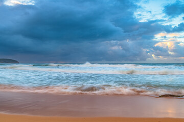 Sunrise at the seaside with rocks and rain clouds