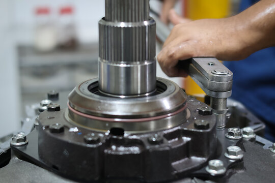 Close-up of a mechanic hand using torque wrench tighten bolts when assembling scavenge pump transmission at workshop.
