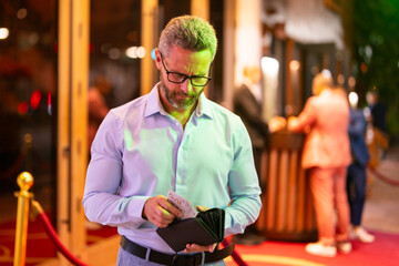 Rich business man holding wallet with money. Rich businessman counting dollars bills money. Wealthy rich man with a wallet and money cash. Businessman in urban nightlife hold wallet. Rich lifestyle.