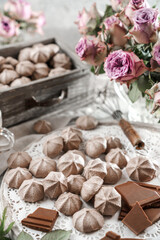 Chocolate meringues, zephyr, on lace napkin with cup of coffee and rose flowers on light background. Sweets, dessert and pastry, homemade cakes, top view