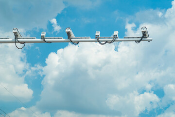 Traffic surveillance cameras mounted against a clear blue sky with scattered clouds