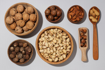Various nuts in wooden bowls on a gray background