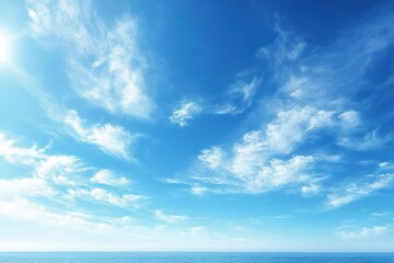Bright blue sky with scattered wispy white clouds over calm ocean horizon during daytime