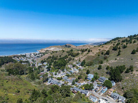 Aerial view of residential neighborhoods, coastal roads, and the Pacific Ocean from the hillside above Linda Mar Valley in Pacifica, California.