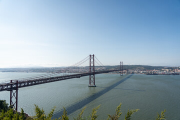 Fototapeta premium High vantage view of Lisbon’s 25 April Bridge casting shadow on the river surface