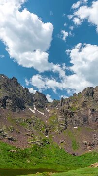 Vertical Time Lapse, Clouds Moving Above Wet Mountains Peaks and Alpine Lake on Sunny Summer Day