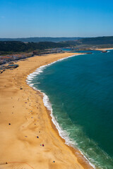 Sweeping view of Nazaré beach from the cliff, curving along the blue ocean