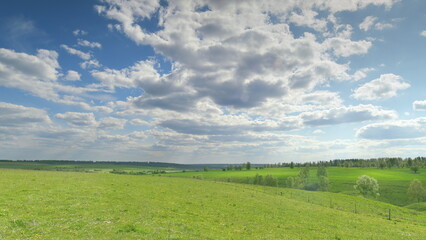 Fototapeta premium The Lush and Vibrant Green Fields Stretch Out Underneath a Beautiful and Clear Sky Time lapse.