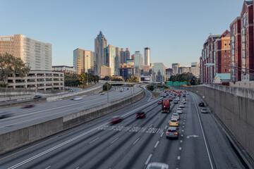 Downtown Atlanta Skyline showing several prominent buildings, highways, cars and hotels under a golden hour sunset.