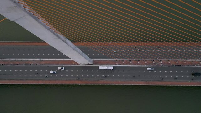 Traffic flows smoothly over modern bridge with orange cables during sunset