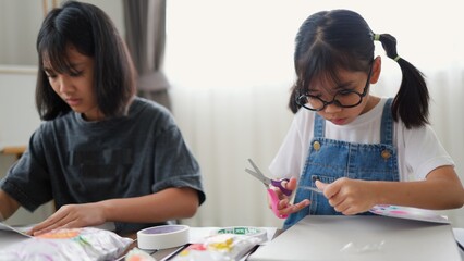 Asian girls doing creative DIY activity at home, developing skills and imagination in a...