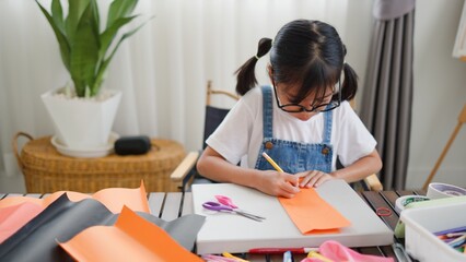 Asian girl focused on making a DIY craft project at home using a compass and colorful paper, promoting creativity, fine motor skills, and fun learning in a homeschool setting.