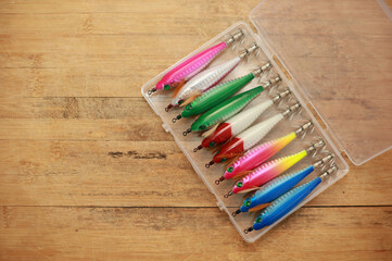 Squid bait is in a plastic box on a wooden floor with space for copying.