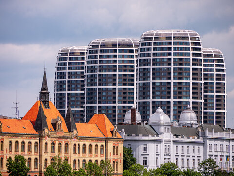 Modern Sky Park towers behind historic Comenius University and high school buildings in Bratislava, Slovakia, showing contrast between old and new architecture.