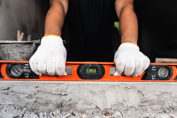 Construction worker using level tool at building site focused inspection urban environment close-up...