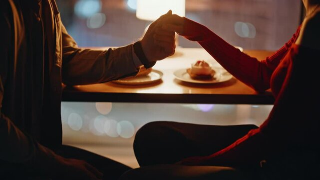 Tender couple holding hands at romantic night date in restaurant closeup. 