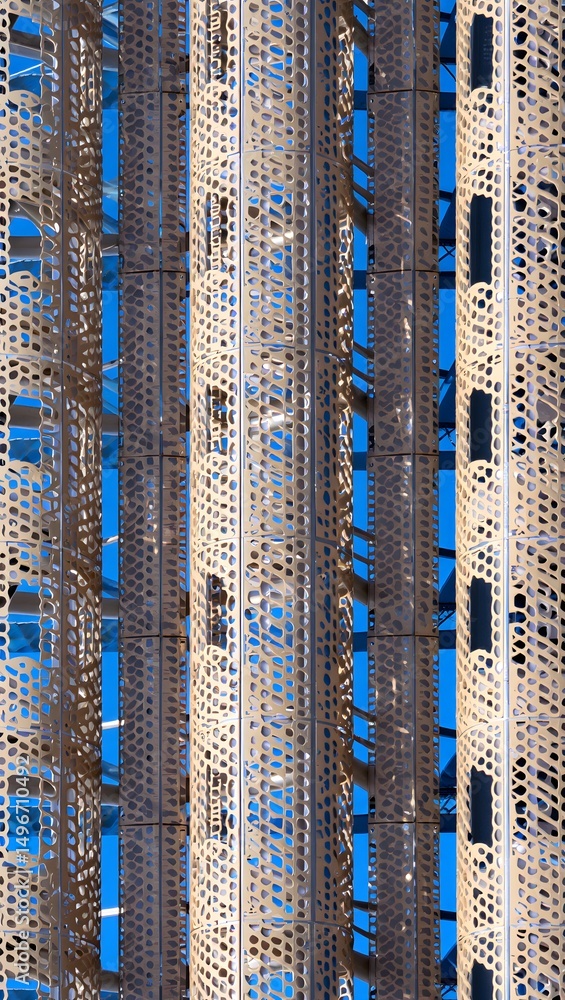 Poster an architectural marvel of repeating patterns, featuring a tall building with intricate metal framew
